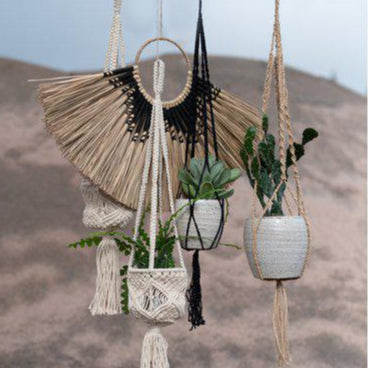 Set of hanging planters with tassels against a neutral background