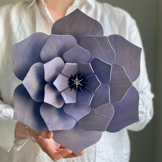 Person holding a large paper flower against a neutral background