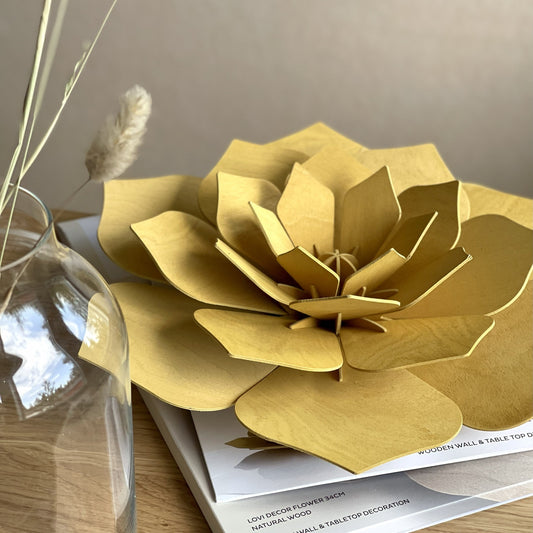 Gold paper flower on a stack of books with a vase in the background